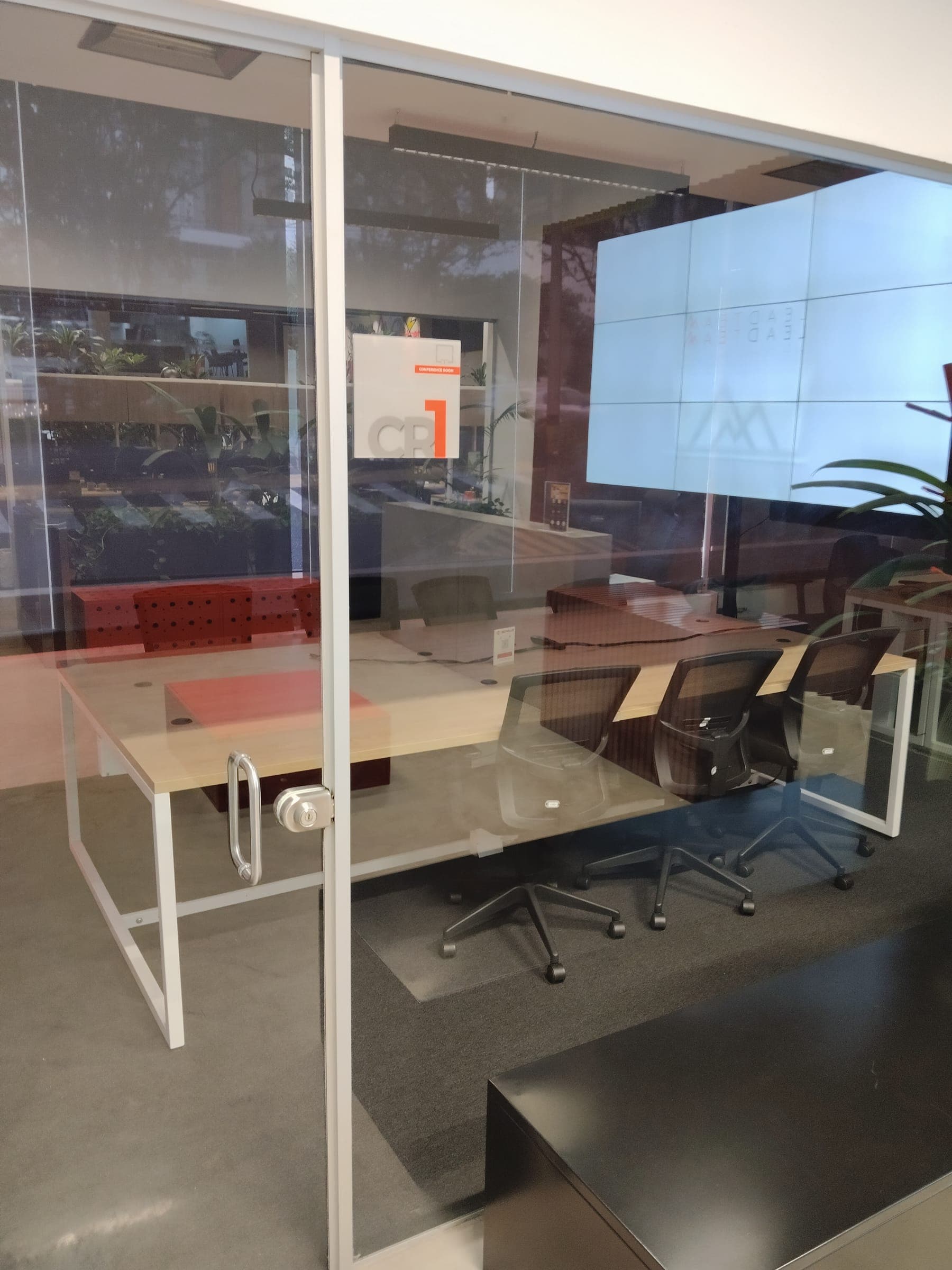 Glass-walled conference room with a large table and a video wall